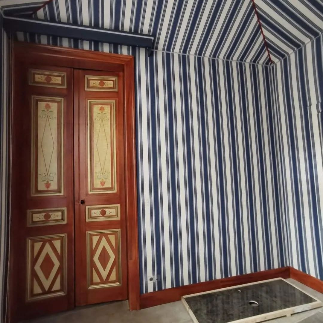 Chambre aux murs rayés bleu et blanc et porte peinte en faux bois